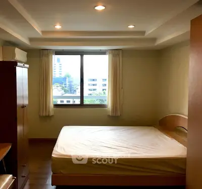 Cozy bedroom with large window and wooden furniture in modern apartment