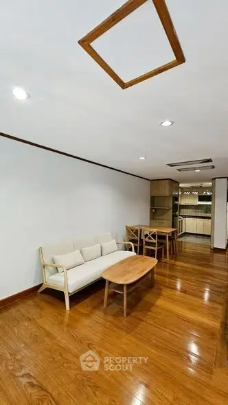 Spacious living room with wooden flooring and modern kitchen in open layout.