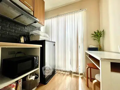 Cozy kitchen with modern appliances and natural light, featuring a compact fridge and microwave.