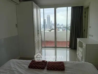 Spacious bedroom with stunning city view from large windows and balcony access.