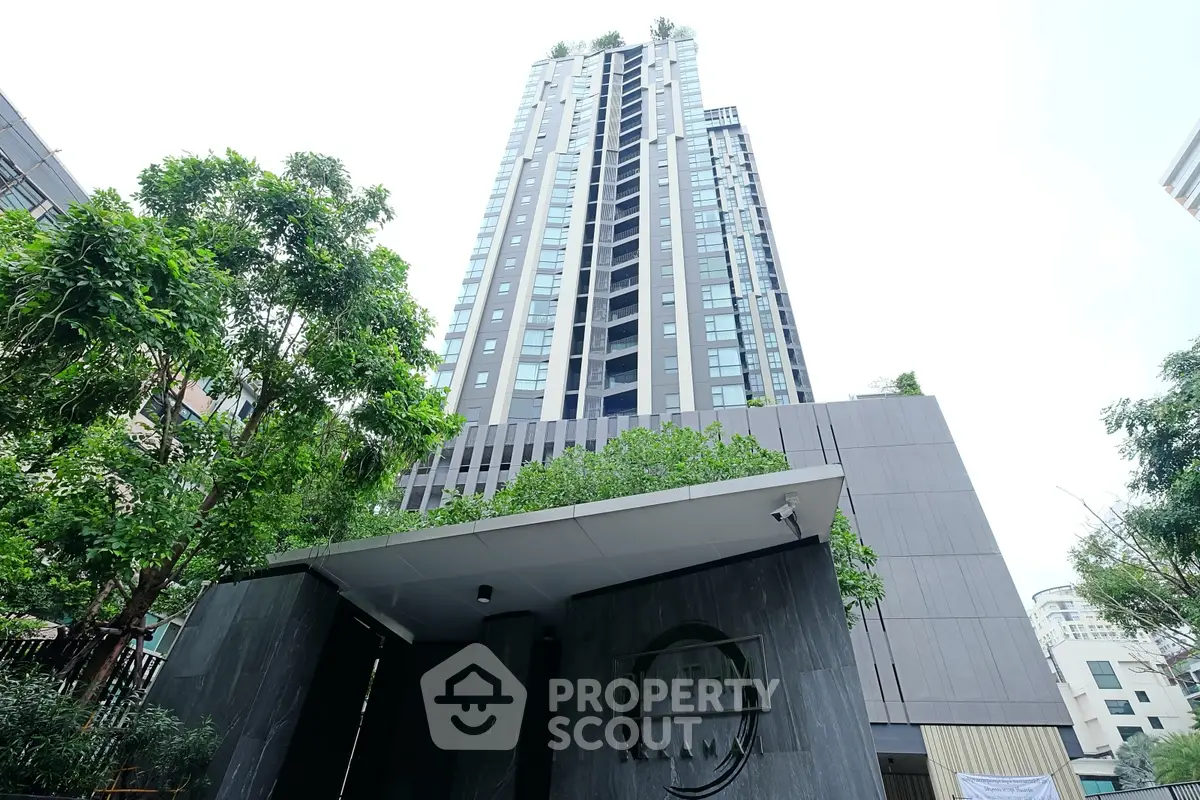 Modern high-rise building with lush greenery and sleek entrance in urban setting.