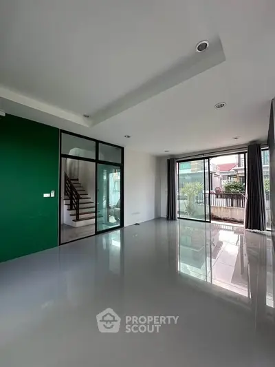 Spacious modern living room with large windows and green accent wall