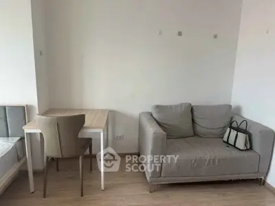 Cozy living area with modern sofa and compact study desk in a minimalist apartment.