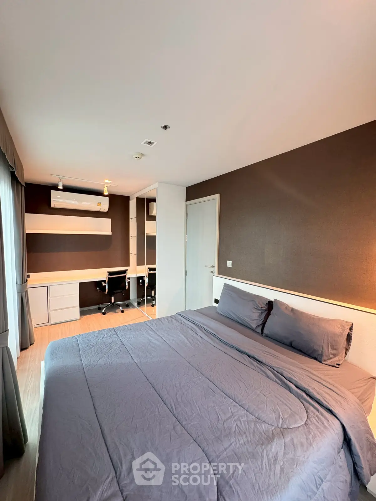 Modern bedroom with stylish decor and workspace, featuring a comfortable bed and sleek furniture.