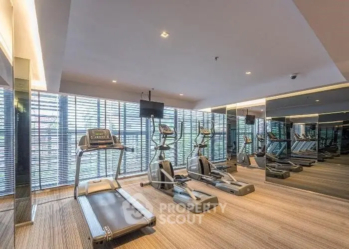 Modern gym with state-of-the-art equipment and mirrored walls in luxury residential building.
