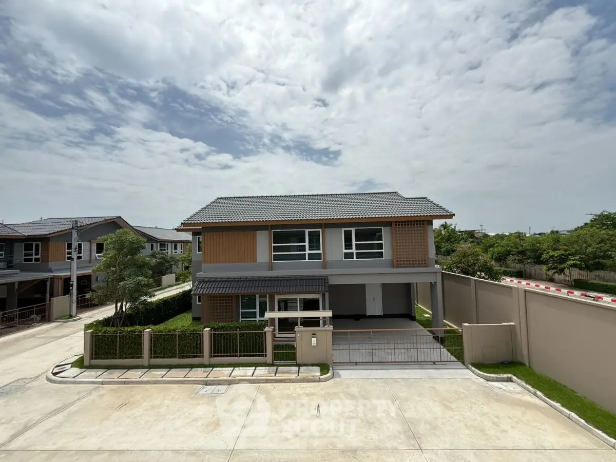 Modern two-story house with spacious driveway and lush greenery in a serene neighborhood.