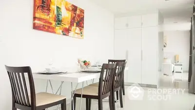 Modern dining area with sleek white furniture and vibrant artwork