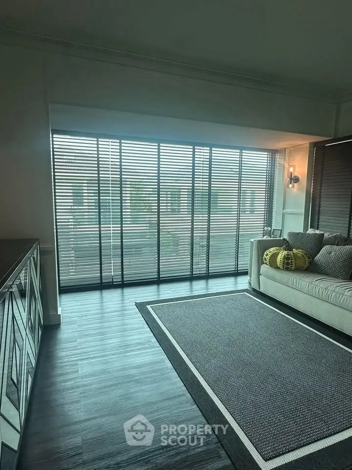 Spacious living room with large windows and modern decor, perfect for relaxation and entertaining.