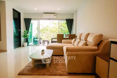Spacious living room with modern furniture and large windows opening to a balcony with greenery view.