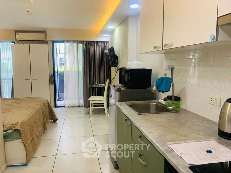 Modern studio apartment with open kitchen and cozy bedroom area, featuring sleek appliances and natural light.
