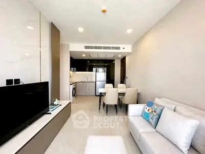 Modern living room with open kitchen, stylish furniture, and bright lighting.