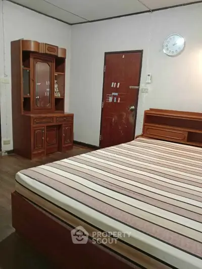 Cozy bedroom with wooden furniture and striped mattress in a serene setting.
