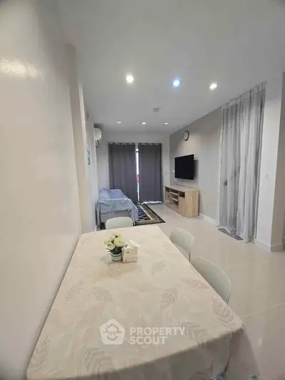 Modern living room with dining area and TV, featuring neutral tones and cozy ambiance.