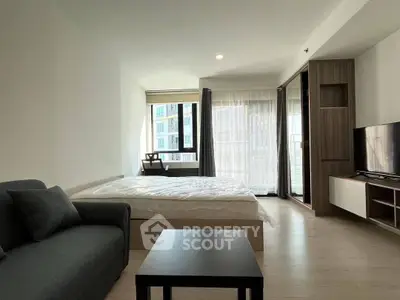 Modern studio apartment with large windows and stylish furnishings in a high-rise building.