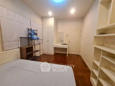 Cozy bedroom with wooden flooring, built-in shelves, and soft lighting