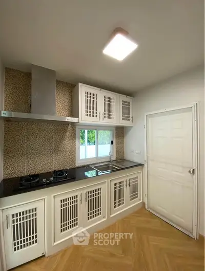 Modern kitchen with closed layout and gas stove, featuring sleek cabinetry and stylish backsplash.