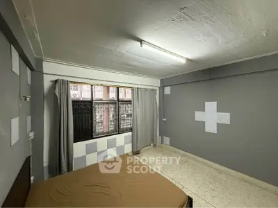 Spacious bedroom with large window and minimalist decor in urban apartment