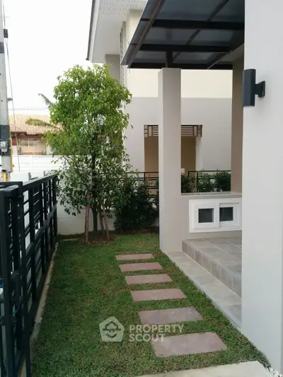 Charming modern home exterior with lush garden and inviting entrance pathway.