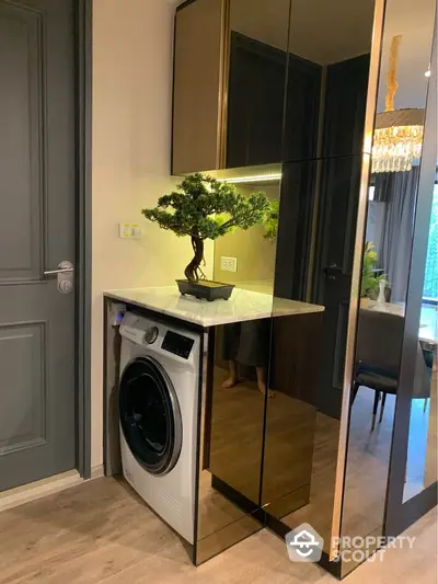 Modern apartment interior with stylish washing machine and bonsai plant