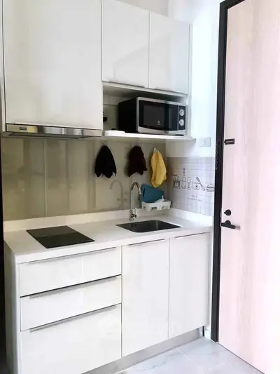 Modern compact kitchen with sleek white cabinets and built-in microwave