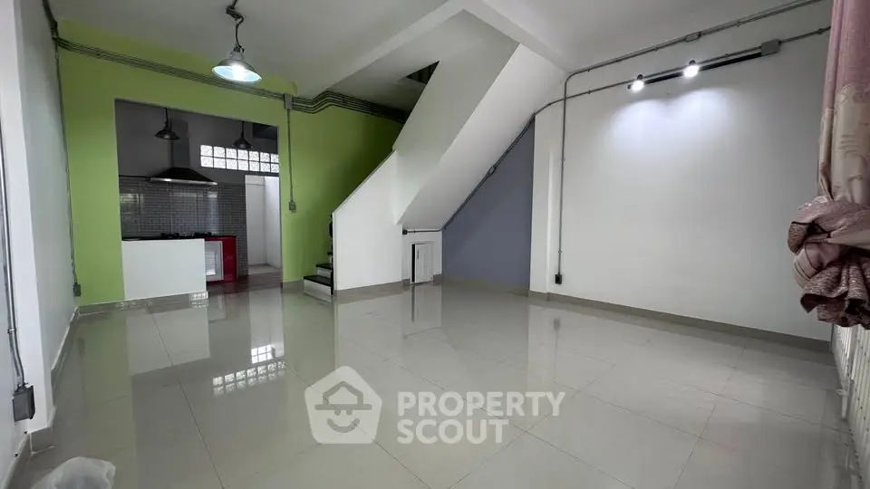 Spacious open-plan living area with modern kitchen and staircase, ideal for contemporary living.