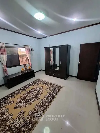 Spacious bedroom with elegant wardrobe and large window, perfect for comfortable living.