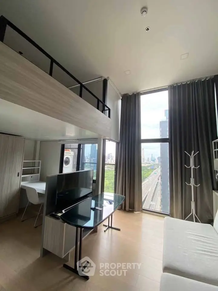 Modern loft apartment with high ceilings and city view, featuring a sleek living area and workspace.