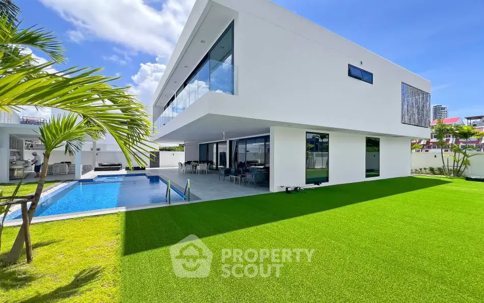 Luxurious modern villa with pool and lush green lawn, perfect for upscale living.