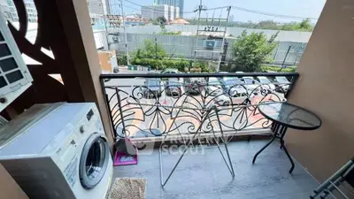 Charming balcony with city view, washing machine, and cozy seating area.