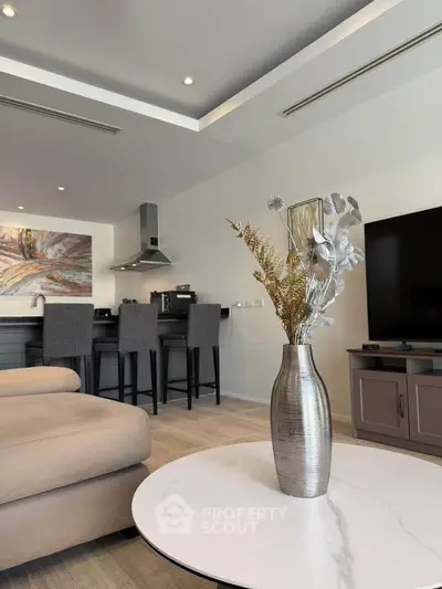 Modern living room with elegant decor and open kitchen layout, featuring a stylish vase centerpiece.