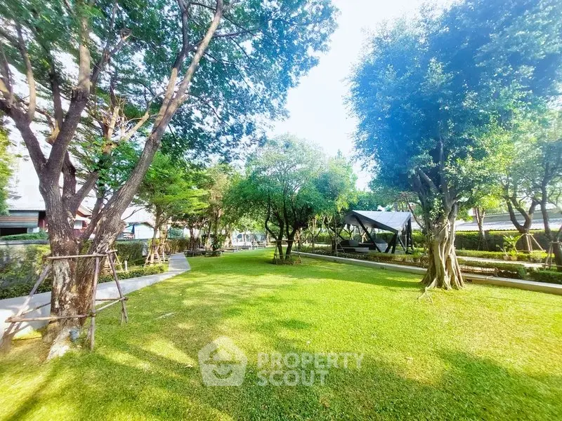 Lush green garden with mature trees and serene pathways in a residential community.