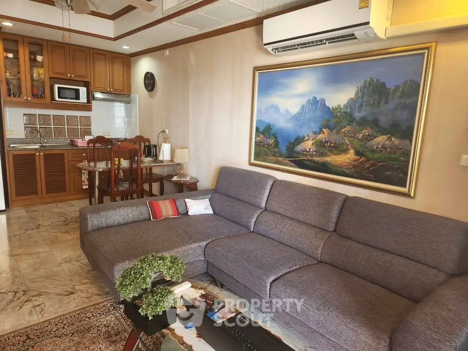 Spacious living room with modern sofa and open kitchen layout, featuring elegant decor and artwork.