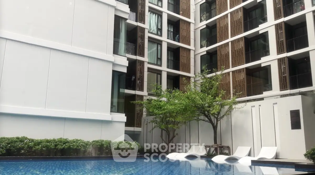 Modern apartment building with poolside relaxation area and stylish architecture.