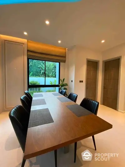 Elegant dining room with modern table and chairs, large window view of lush greenery.