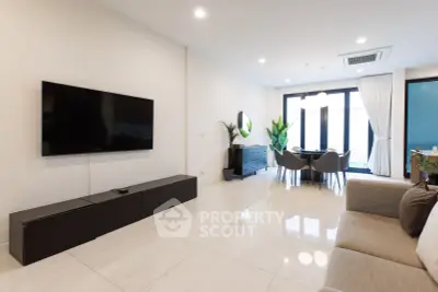 Spacious modern living room with sleek furniture and large TV, perfect for relaxation and entertainment.