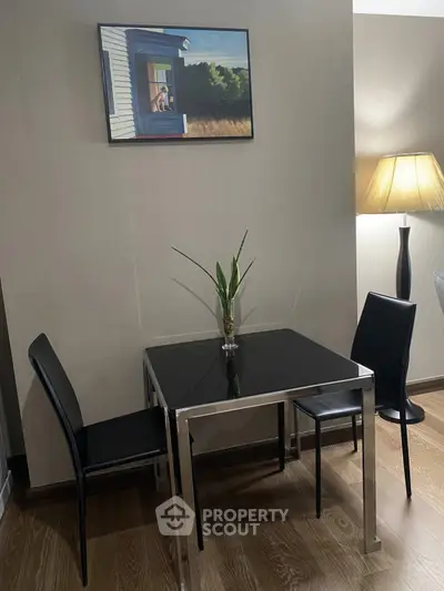 Modern dining area with sleek black table and chairs, stylish decor and warm lighting.