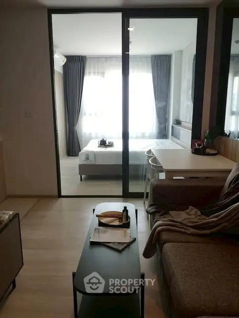 Modern apartment interior with cozy living room and bedroom separated by glass partition.