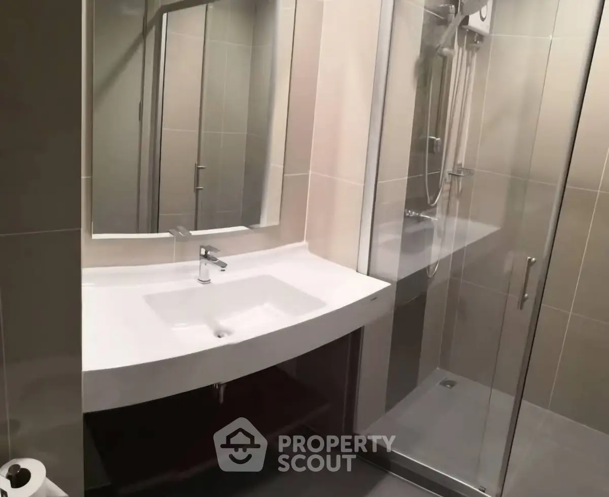 Modern bathroom with sleek sink and glass shower enclosure in contemporary design.