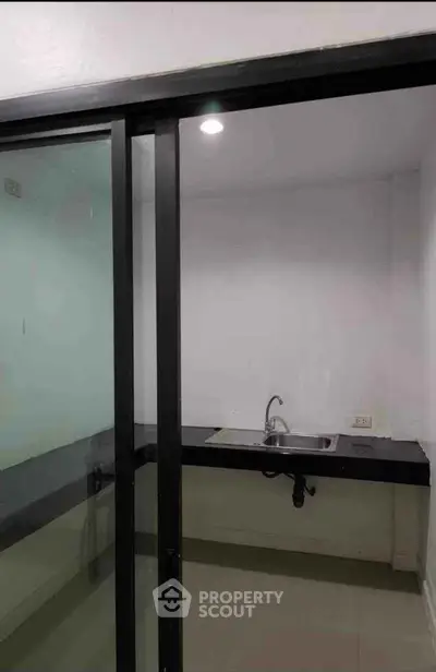 Modern minimalist kitchen with sleek black countertops and sliding glass door.