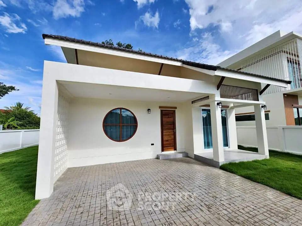 Modern minimalist house exterior with unique circular window and lush green lawn.