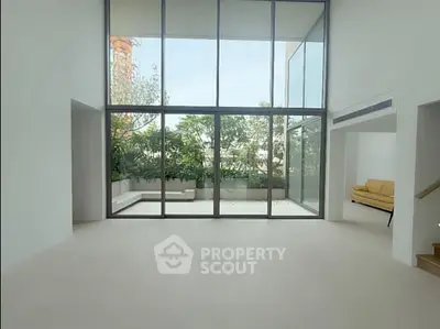 Spacious modern living room with floor-to-ceiling windows and garden view