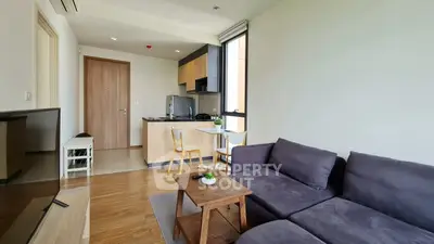 Modern living room with cozy sofa and open kitchen layout in a stylish apartment.
