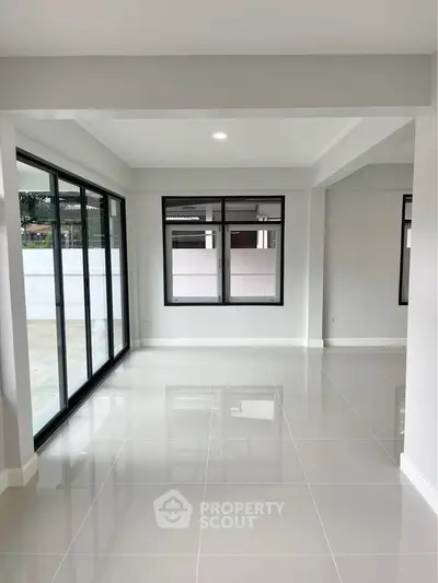 Spacious modern living room with large windows and glossy tiled floors