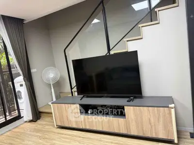Modern living room with sleek TV setup and stylish staircase design