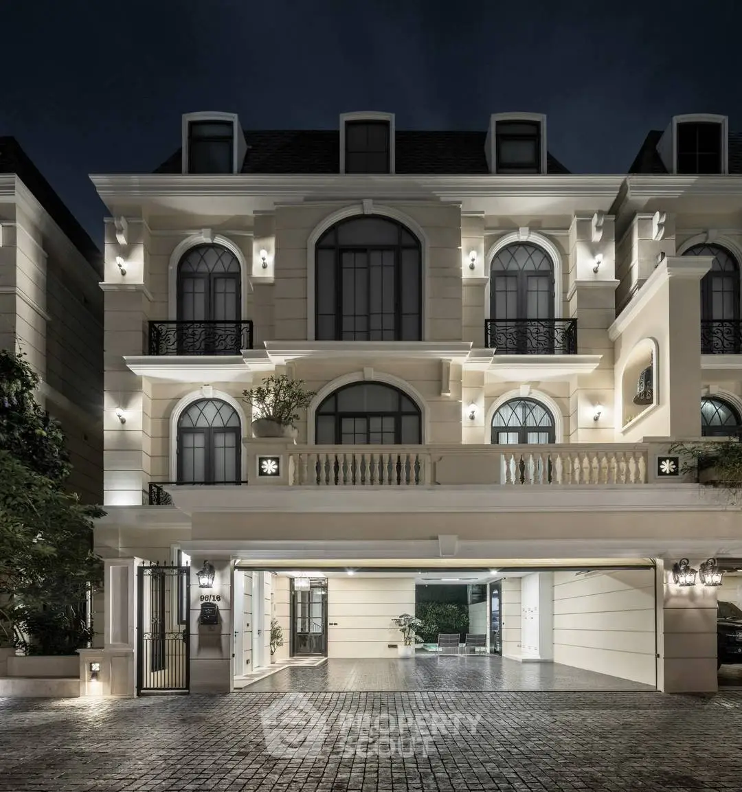 Luxurious three-story mansion with elegant facade and ambient night lighting, showcasing grandeur and sophistication.