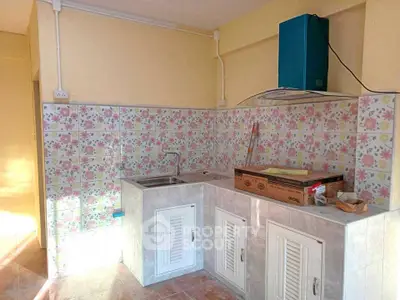 Charming kitchen with floral tile backsplash and modern range hood, perfect for cozy cooking experiences.