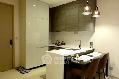 Modern kitchen with sleek design and dining area, featuring elegant lighting and contemporary finishes.