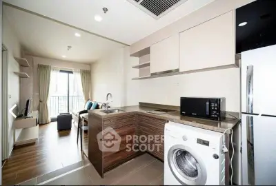 Modern open-layout kitchen with washing machine and living area in stylish apartment