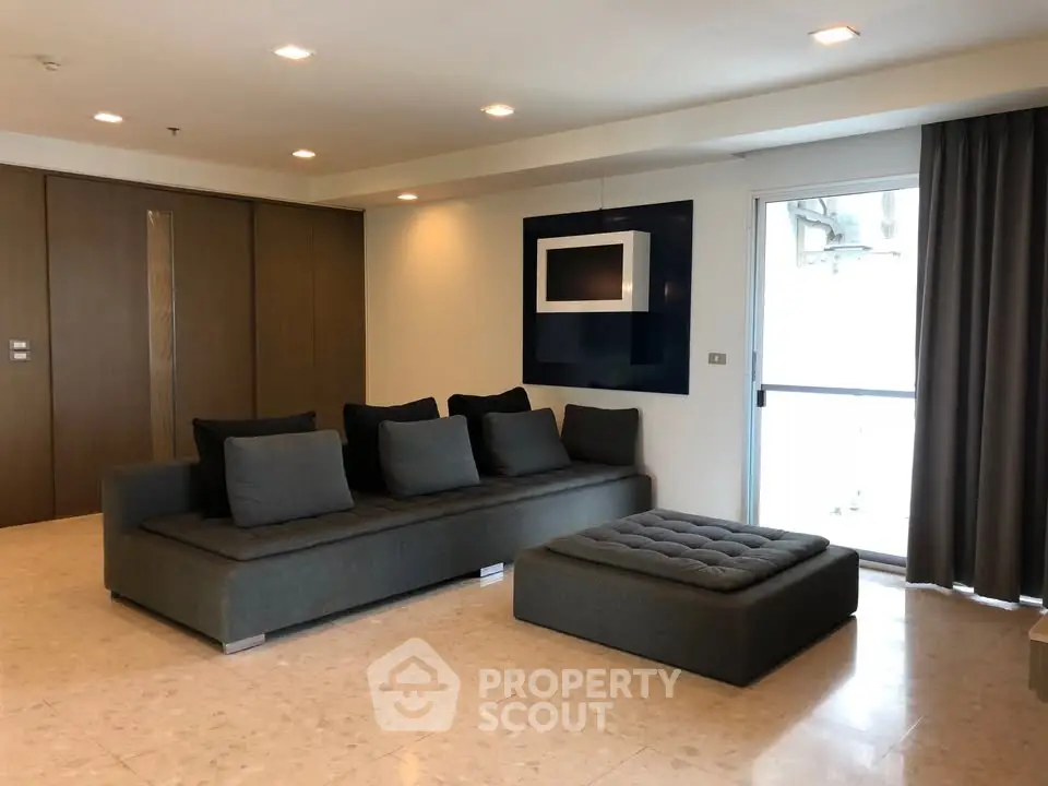 Spacious modern living room with elegant gray sofa and large window for natural light.