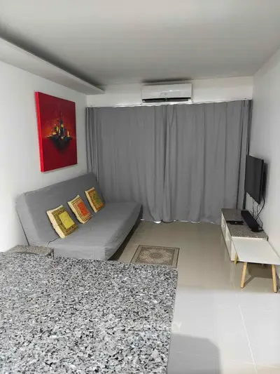 Modern living room with sleek design, featuring a comfortable sofa, wall-mounted TV, and stylish decor.